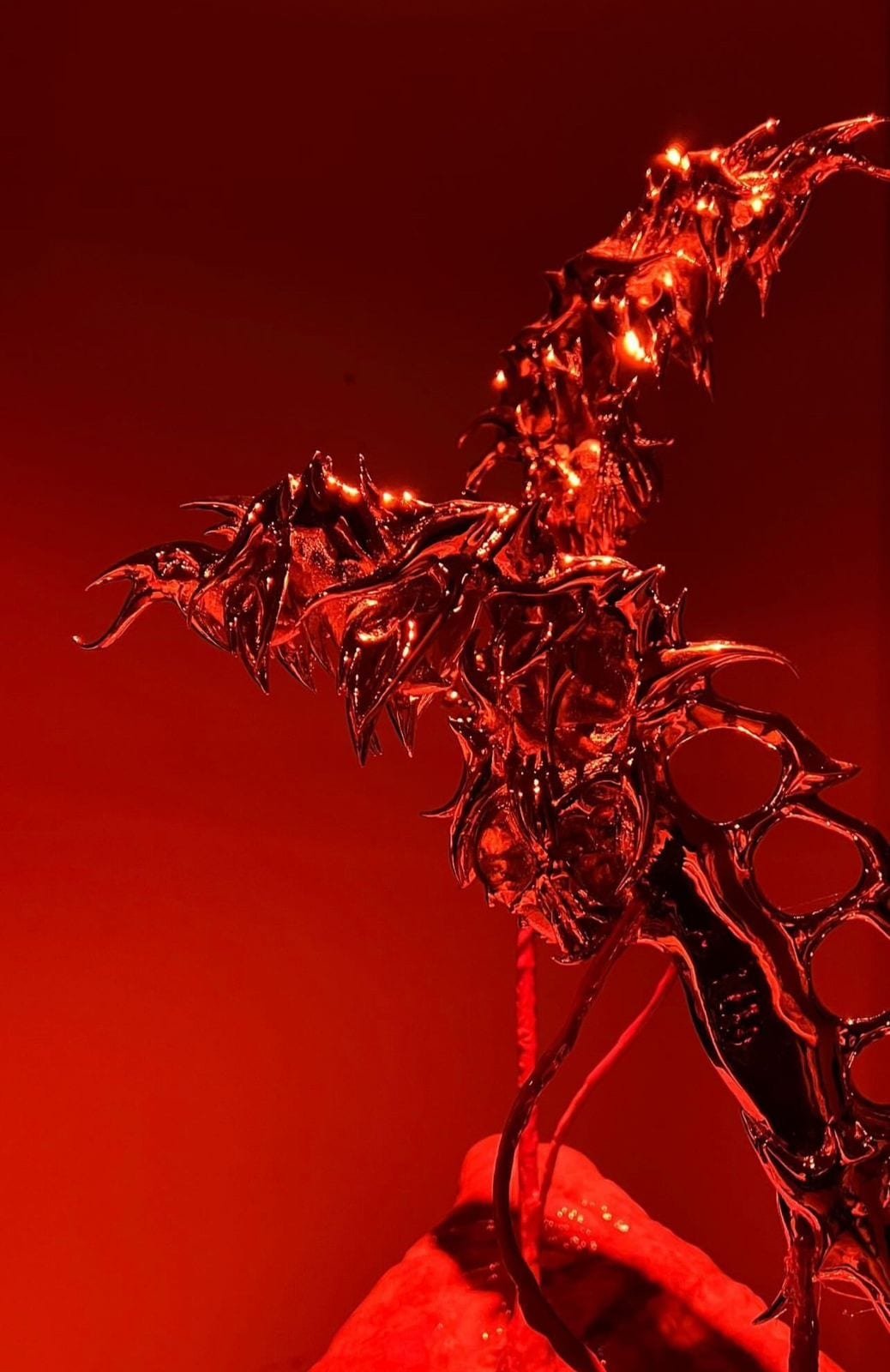 Daga de la línea Berserk x Milton Sanz, de filo ramificado, en rojo translúcido sobre fondo rojo